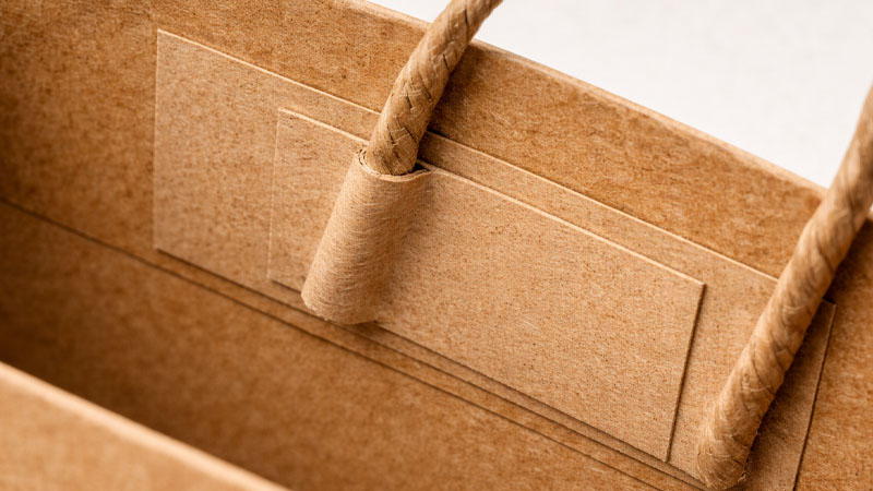 Reinforcement patch inside a kraft paper bag strengthening the handle attachment