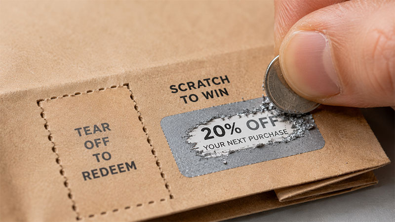 Hand scratching silver coupon on paper bag